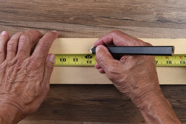 Hochwinkelaufnahme einer Zimmermannshand mit einem Maßband, um — Stockfoto