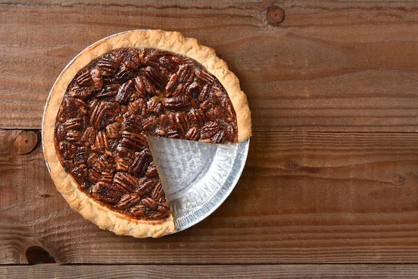 A Pecan pie with a slice cut out. Horizontal format on a rustic — Stock Photo, Image