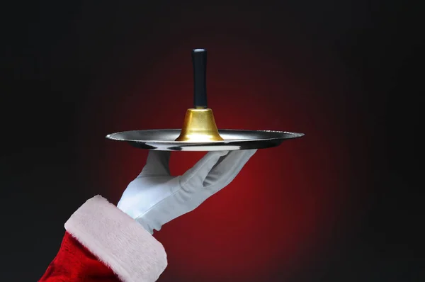 Closeup of Santa Claus hand holding a bell on a silver tray. Hor — Stock Photo, Image