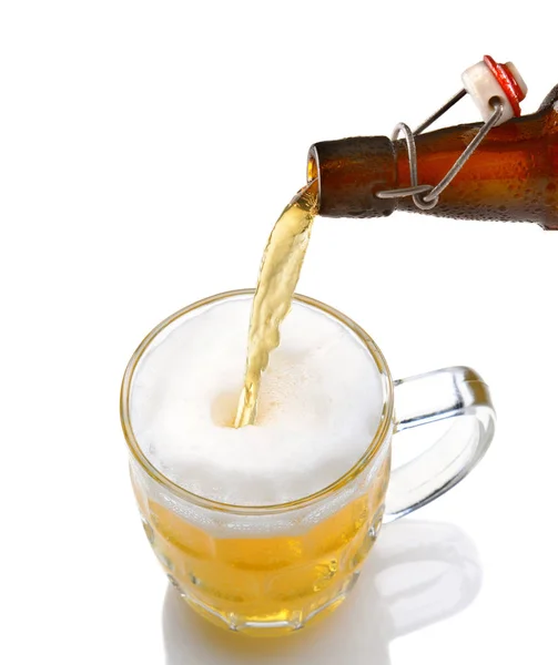 Cold beer pouring from a bottle into a mug on a white background — Stockfoto