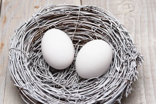 素朴な白い板の上に小枝の巣の中に2つの鶏の卵 — ストック写真