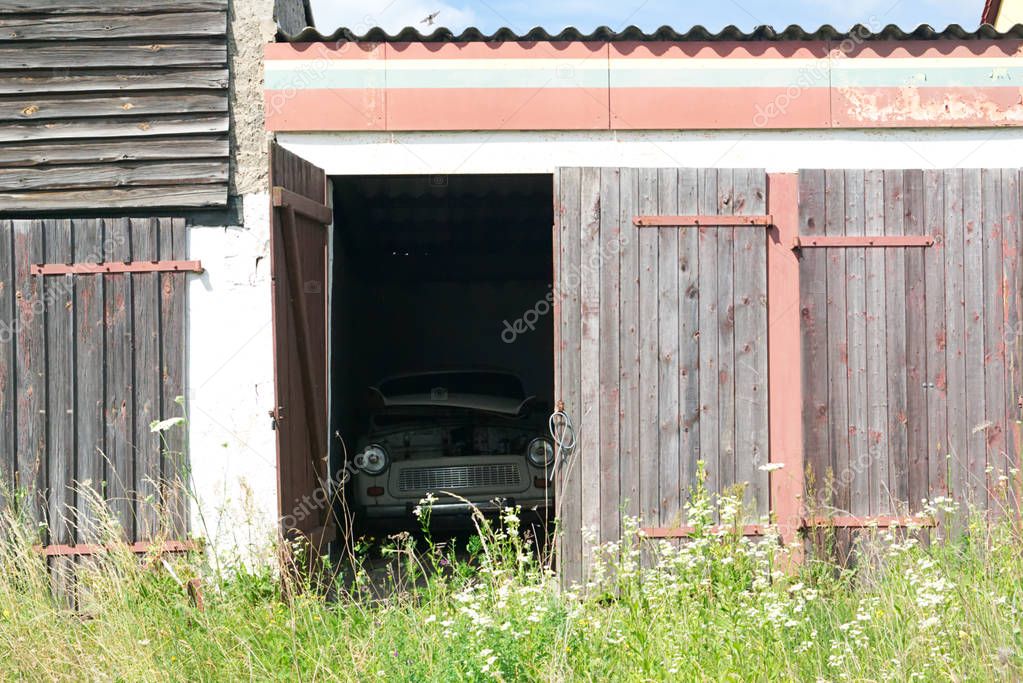 old ruined garage with vintage car through open door