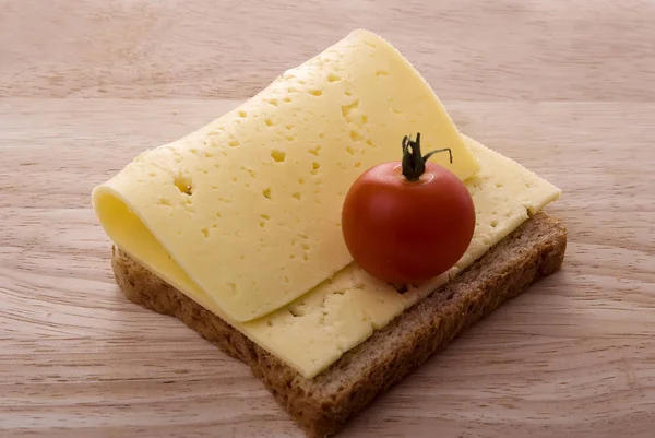 Sandwich al formaggio aperto con pomodoro su tagliere di legno Foto Stock