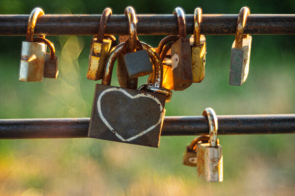 Padlock on a wire garden fence. Shot with vintage lens. Love and friendship.