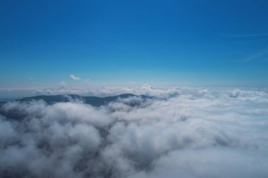 Bulutlar ve dağ zirveleri havadan görünümü.