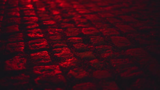 Mouillé éclairé par la lumière rouge pavé rue pavée la nuit  