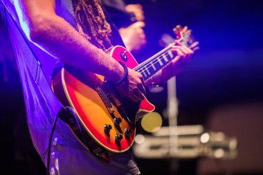 Sahne Alanı'nda elektrik bas gitar çalmaya gitarist. Renkli, yumuşak odak ve bulanıklık arka plan.