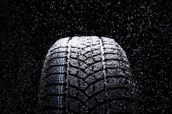 冬季汽车轮胎在黑色背景上的雪 — 图库照片