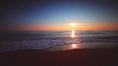 Deniz ve plaj üzerinde gündoğumu. Dalgalar kum yıkama.