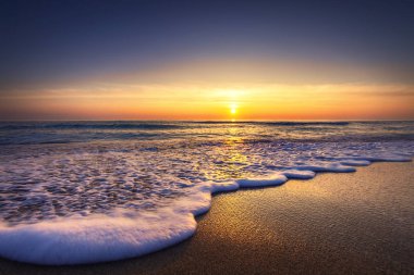 Deniz ve plaj üzerinde gündoğumu. Dalgalar kum yıkama.