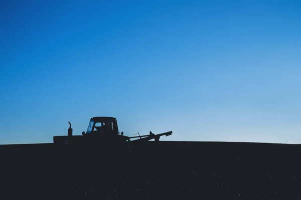 Tractor on the field. Silhouette against a blue sky