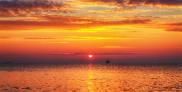Восход солнца над морской водой и лодкой — стоковое фото