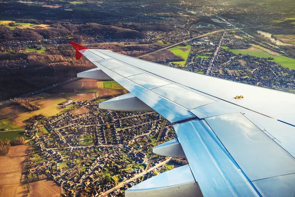 Wing of an airplane flying above the city land — Stock Photo, Image