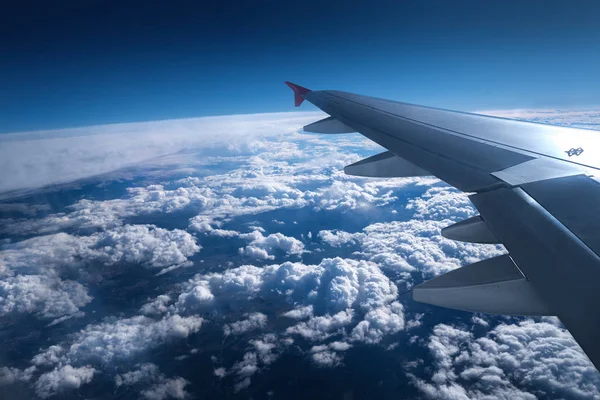 Ala de un avión volando sobre el cielo con nubes y ciudad la —  Fotos de Stock