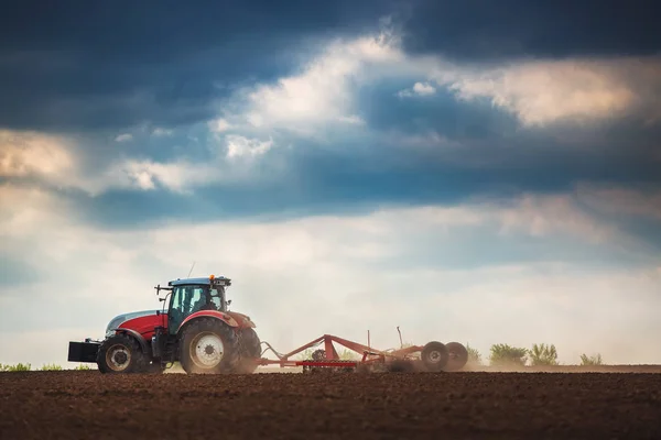 Agricultor en tractor preparando tierra con cultivador de semillero —  Fotos de Stock