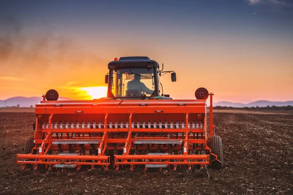 Pôr do sol bonito, agricultor em trator preparando terra com cama de sementes — Fotografia de Stock