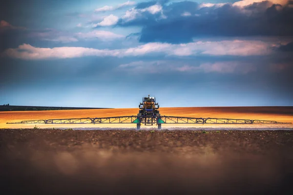 Landbouwtrekker ploegen en sproeien op het veld — Stockfoto