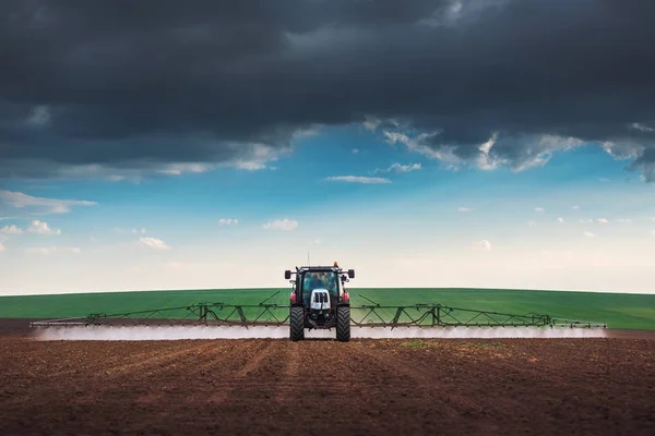 Ackerschlepper pflügt und sprüht auf Feld — Stockfoto