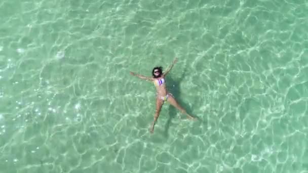 Vue aérienne d'une belle fille en bikini, flottant dans une eau de mer bleue et cristalline des Caraïbes 
