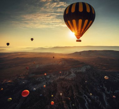 Kapadokya'daki vadide gün doğumunda uçan sıcak hava balonları. Türkiye.