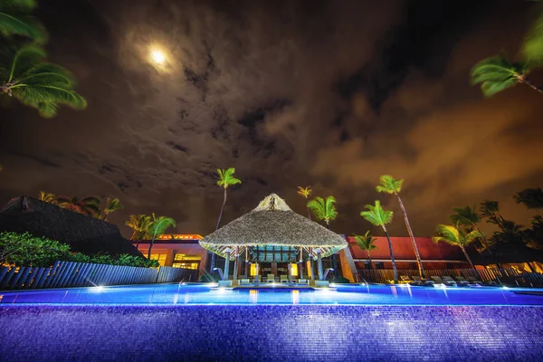 Бассейн и пальмы на роскошном курорте по ночам — стоковое фото