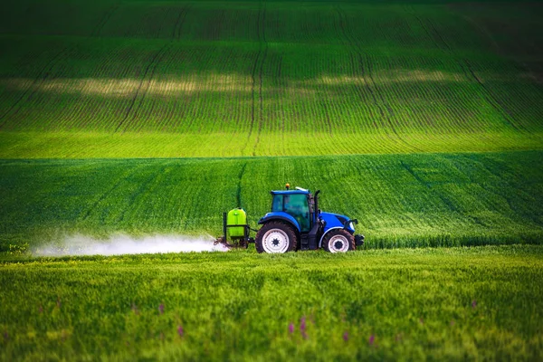 Farming tractor plowing and spraying on field — Stock Photo, Image