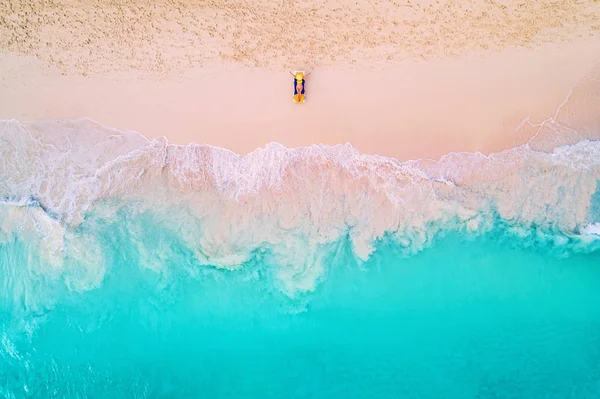 Вид с воздуха на женщину на пляже в бикини лежащей и загорающей — стоковое фото