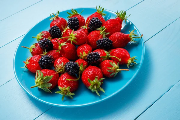 Berry campur dengan stroberi dan raspberry di piring dan meja kayu — Stok Foto