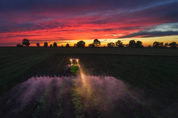 Traktor sprutnings fält på våren, Sunset shot — Stockfoto