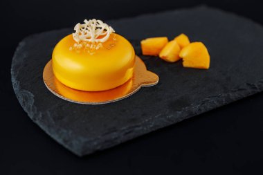 Siyah taş plaka üzerinde mango püresi ve krem ile Mus kek