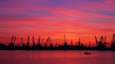 Bulgaristan'ın Varna limanında endüstriyel vinçler ve kargo gemileri üzerinde gün batımı 