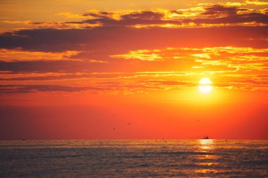 Yelkenli bir balıkçı teknesiyle denizin üzerinde gün doğumu