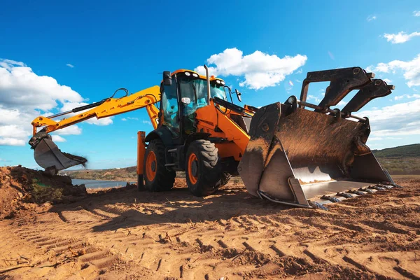 Hjullastare grävmaskin med fält bakgrund under schaktning — Stockfoto