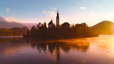 Slovenya, sonbahara kadar Bled Gölü, St. Marys Assumption Kilisesi ile sudaki küçük adada ve güzel gün batımında