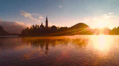 Slovenya, sonbahara kadar Bled Gölü, St. Marys Assumption Kilisesi ile sudaki küçük adada ve güzel gün batımında