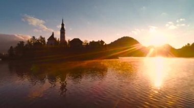 Slovenya, sonbahara kadar Bled Gölü, St. Marys Assumption Kilisesi ile sudaki küçük adada ve güzel gün batımında