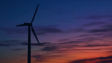 Bir tarlada günbatımında elektrik üretimi için yel değirmenleri