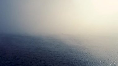 Sis ve yelkenli balıkçı teknesi denizde, havadan gün doğumu manzarası