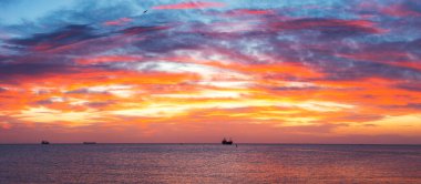 Denizde güneş batıyor. Yelkenli kargo gemisi manzaralı.