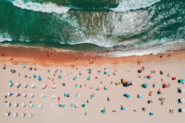 Kumsalın üstündeki hava manzarası. Şemsiyeler, kum ve deniz dalgaları. Yaz tatili