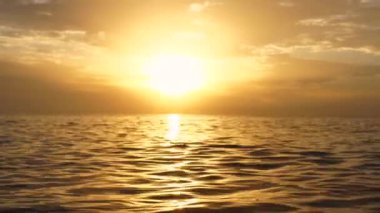 Altın gün doğumu, yanan gökyüzü deniz dalgaları üzerinde dramatik bulutlarla