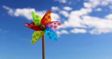 Rüzgarın mavi gökyüzüne ve güneşli yaz gününde ağır çekimde beyaz bulutlara estiği renk fırıldak. Özgürlük ve çocukluk. Oyuncak çevirici