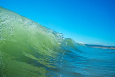 Deniz dalgası yakın, alçak açılı, güneşli bir çekim..