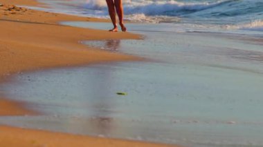 Okyanus sahili gün doğumu. Kadın sabahın erken saatlerinde kumda rahatlamak için yürüyor.