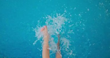 Mutlu su sıçratma ayakları mavi yüzme havuzunda neşeli ve rahatlatıcı yaz aktivitelerini temsil ediyor.