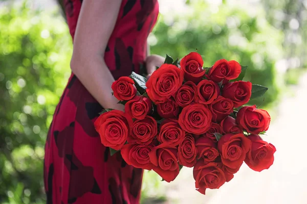 Mani femminili in possesso di bouquet di bellezza di rose rosse — Foto Stock