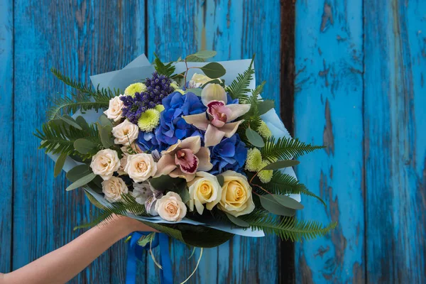 Weibliche Hände mit einem schönen Strauß roter Rosen — Stockfoto