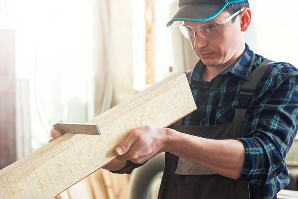 İşçi ölçümleri bir ahşap tahta yapar — Stok fotoğraf