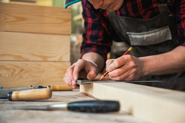 El trabajador hace las medidas de la tabla de madera — Foto de Stock