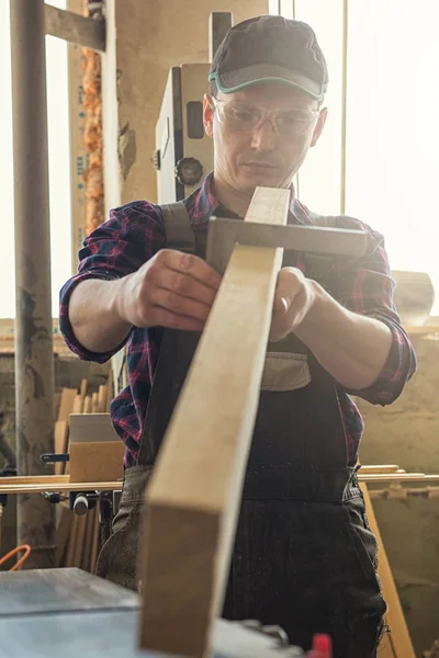 El trabajador hace las medidas de la tabla de madera — Foto de Stock